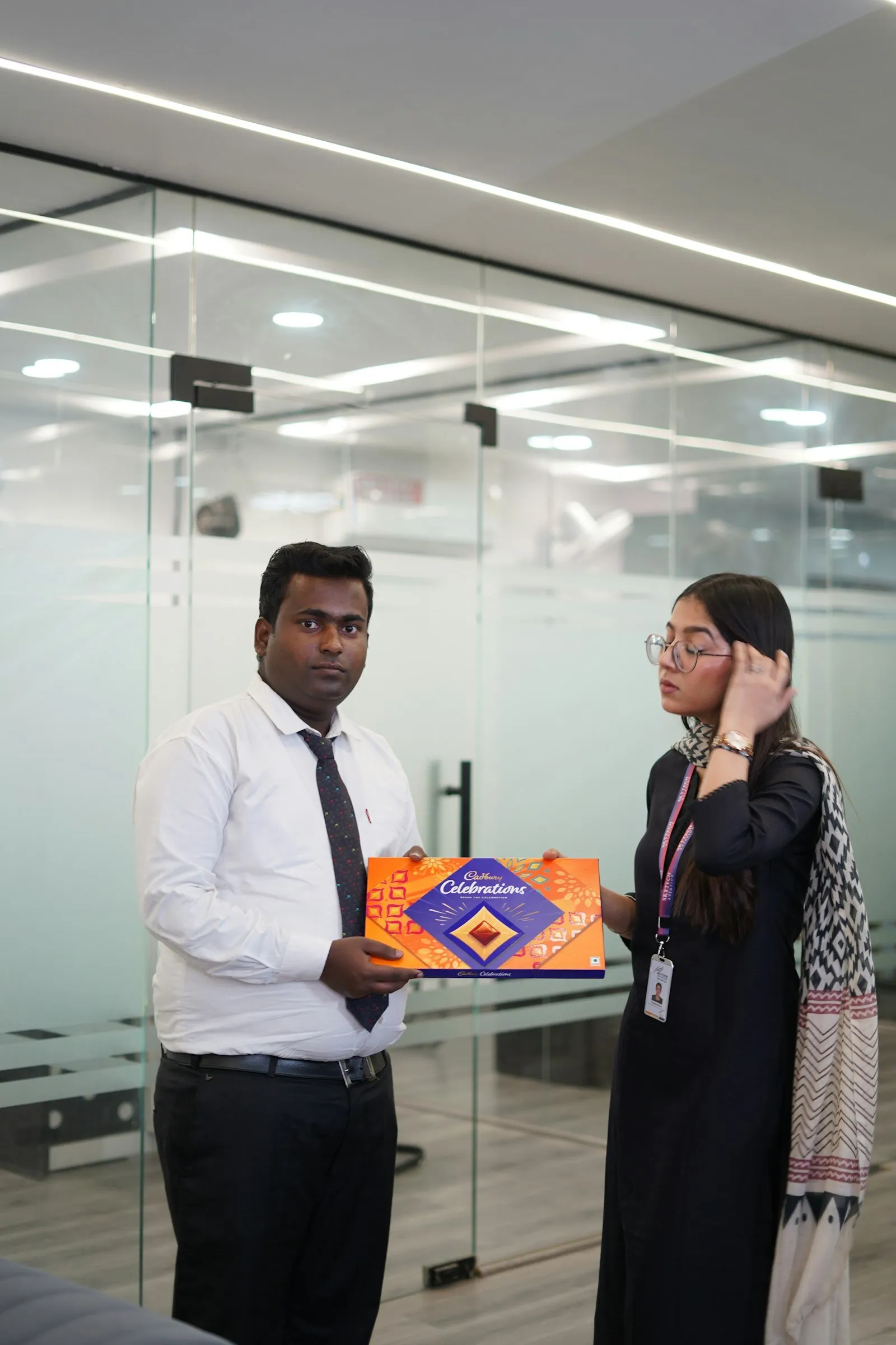 Colleagues exchanging a wrapped gift box in an office