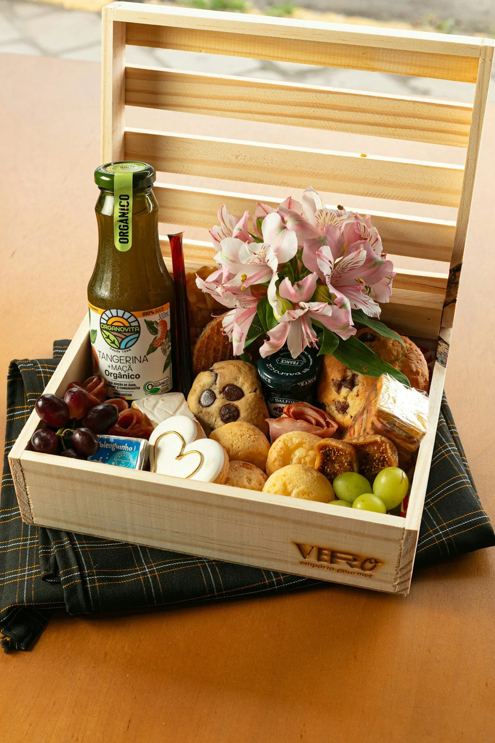 A wooden crate filled with food, flowers, and drink