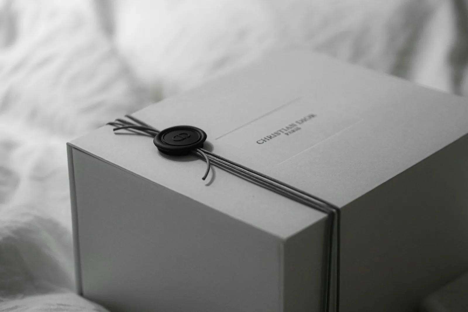 A white gift box tied with ribbon and wax seal